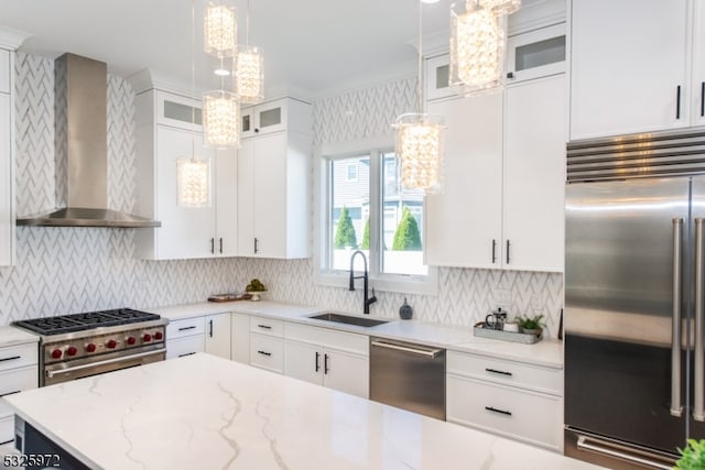 kitchen with high end appliances, wall chimney exhaust hood, sink, and white cabinets