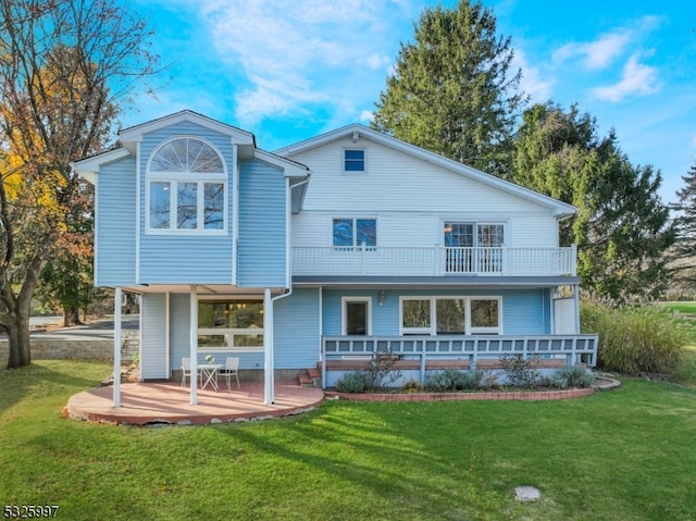 back of house featuring a lawn and a balcony