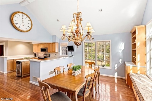 dining area featuring vaulted ceiling with beams, light hardwood / wood-style floors, wine cooler, and a notable chandelier