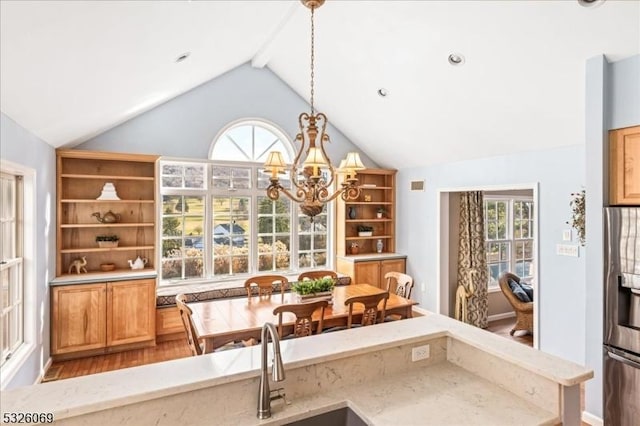 dining area with a notable chandelier, lofted ceiling with beams, and wood-type flooring