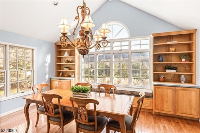 dining area featuring lofted ceiling, light wood-type flooring, and an inviting chandelier