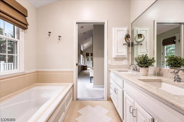 bathroom with vanity, a relaxing tiled tub, tile patterned floors, and a healthy amount of sunlight