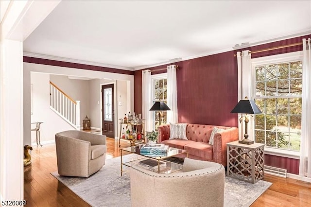 living room featuring crown molding, light hardwood / wood-style flooring, and a healthy amount of sunlight