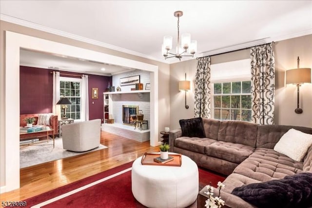 living room featuring a notable chandelier, crown molding, wood-type flooring, and a fireplace