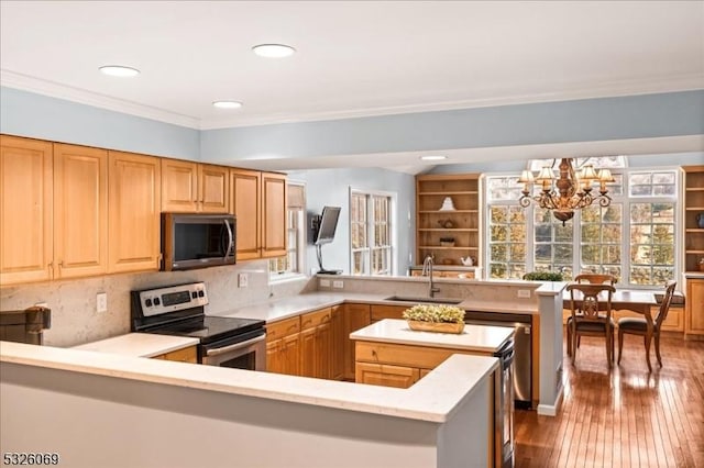 kitchen with kitchen peninsula, sink, stainless steel appliances, and an inviting chandelier