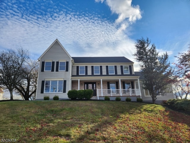 colonial-style house featuring covered porch and a front yard