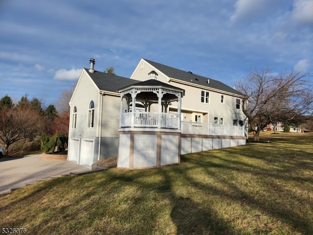 back of house featuring a gazebo, a garage, and a lawn