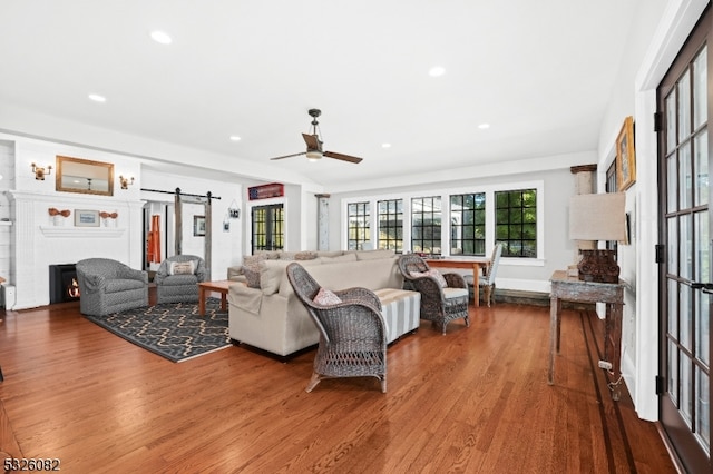 living room featuring wood-type flooring, a barn door, and ceiling fan