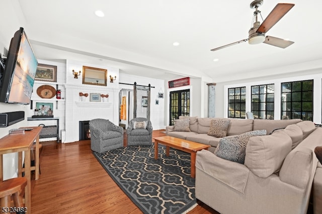 living room featuring a barn door, ceiling fan, and hardwood / wood-style flooring