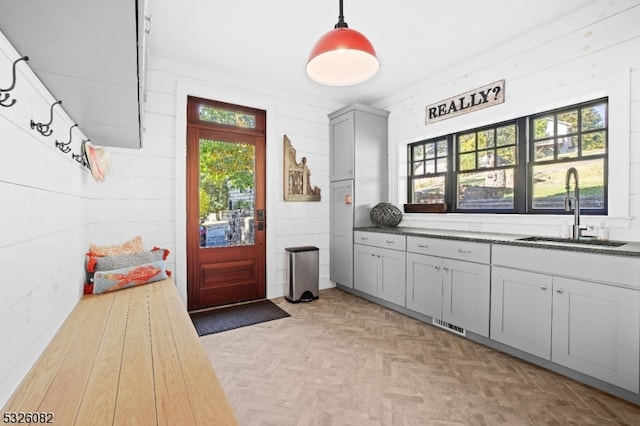 interior space with sink, wooden walls, and light parquet flooring