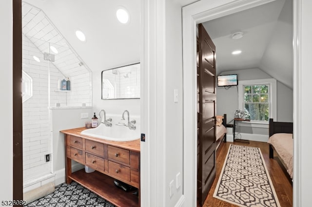 bathroom with a tile shower, vanity, lofted ceiling, and hardwood / wood-style flooring