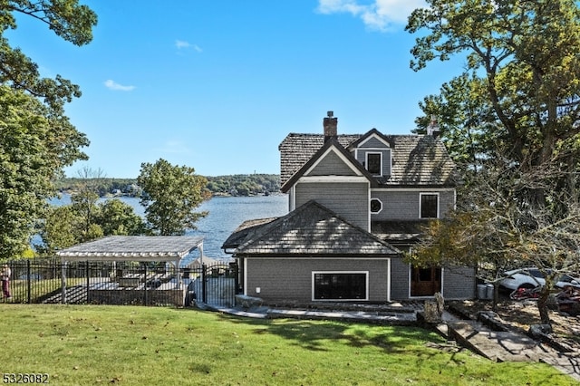 rear view of property featuring a lawn and a water view