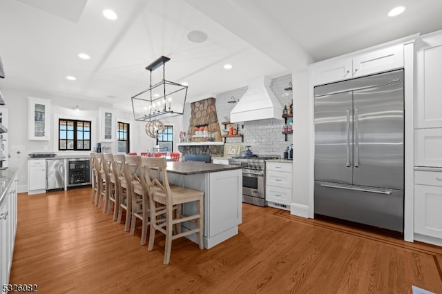 kitchen with white cabinets, a kitchen breakfast bar, high quality appliances, and wood-type flooring