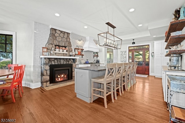 kitchen featuring a fireplace, a kitchen breakfast bar, light hardwood / wood-style floors, and white cabinets