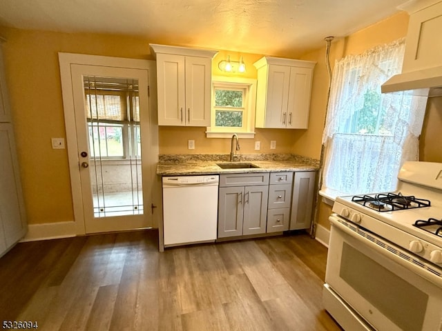 kitchen featuring white appliances, white cabinets, sink, light stone countertops, and light wood-type flooring