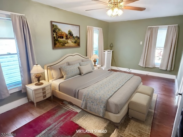 bedroom with multiple windows, ceiling fan, and dark wood-type flooring