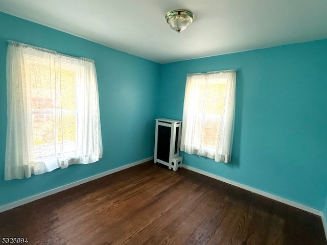 empty room with radiator heating unit and dark wood-type flooring