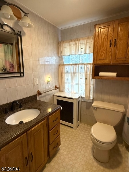 bathroom with vanity, toilet, ornamental molding, and tile walls