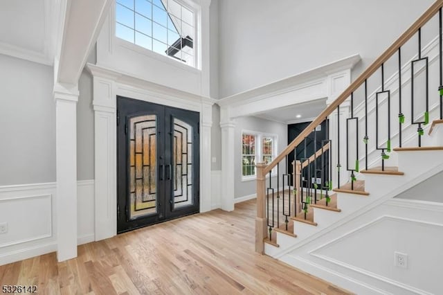 entryway with french doors, a towering ceiling, and light hardwood / wood-style floors