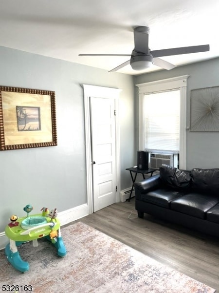 living room with ceiling fan, cooling unit, wood-type flooring, and baseboard heating