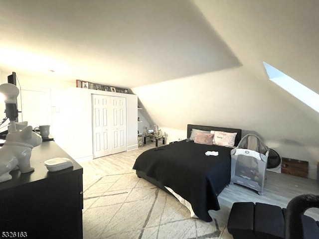 bedroom with a closet, lofted ceiling, and light wood-type flooring