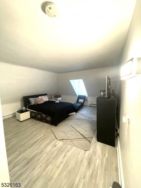 bedroom with light hardwood / wood-style floors and lofted ceiling