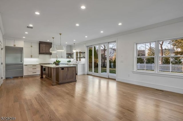 kitchen featuring plenty of natural light, a kitchen island, pendant lighting, and appliances with stainless steel finishes