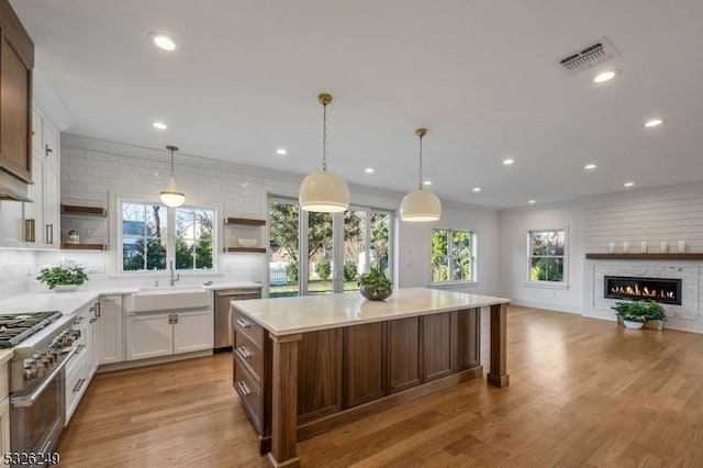 kitchen featuring sink, white cabinets, hanging light fixtures, and light hardwood / wood-style flooring