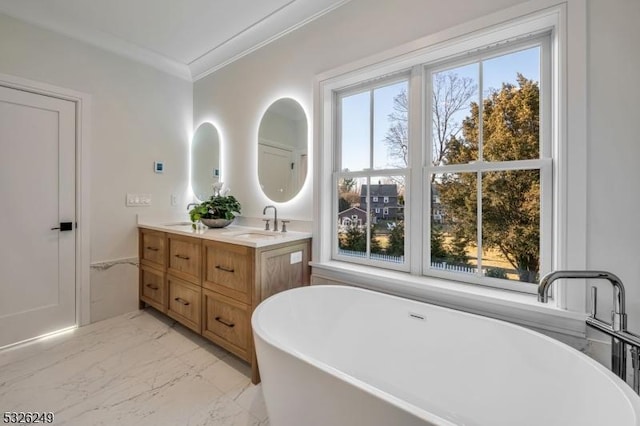 bathroom featuring a tub, a wealth of natural light, vanity, and ornamental molding