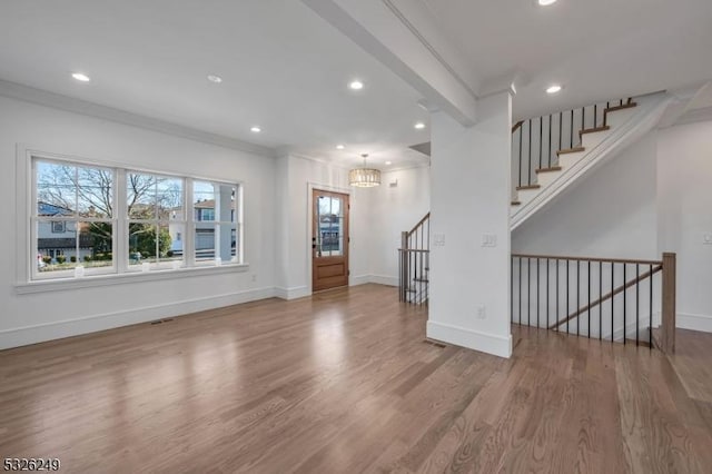 unfurnished living room with hardwood / wood-style floors, a notable chandelier, and ornamental molding