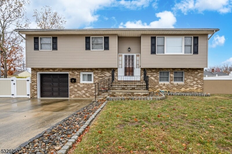 raised ranch with a front lawn and a garage