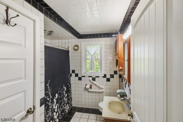 bathroom with tile patterned flooring, toilet, vanity, tile walls, and a shower with shower curtain