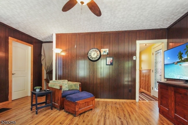 living area featuring light wood-type flooring and wooden walls