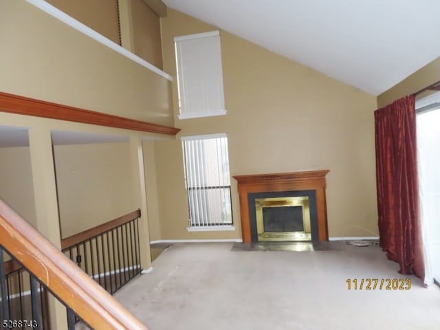 unfurnished living room with carpet flooring and high vaulted ceiling