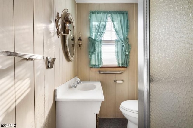 bathroom with vanity, toilet, and wooden walls