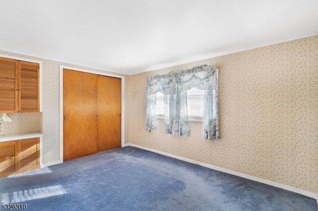 unfurnished bedroom featuring dark colored carpet and a closet