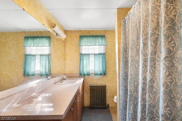 bathroom featuring radiator heating unit, vanity, toilet, and a healthy amount of sunlight