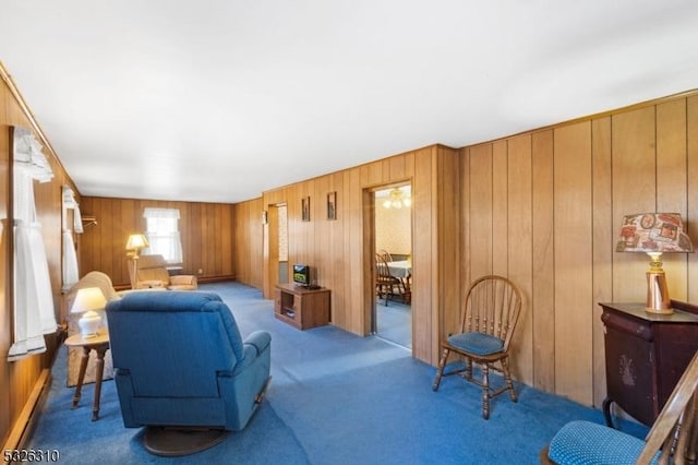 carpeted living room with wooden walls and a baseboard heating unit