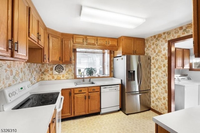 kitchen featuring white appliances, separate washer and dryer, and sink