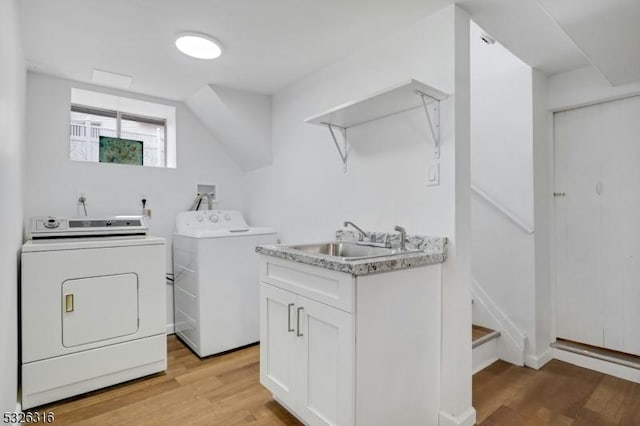 laundry room with laundry area, washing machine and dryer, light wood-type flooring, and a sink