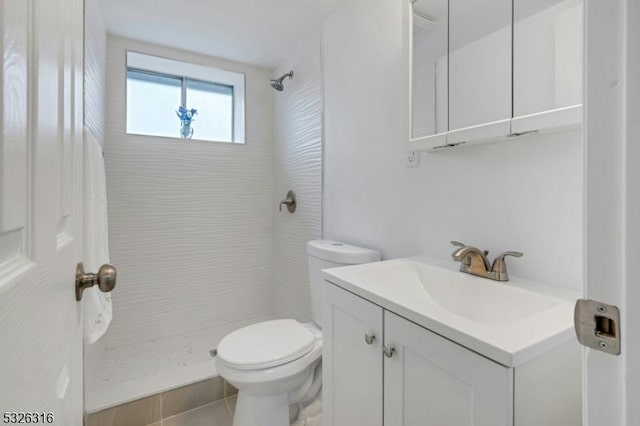 full bath with toilet, tile patterned floors, a tile shower, and vanity