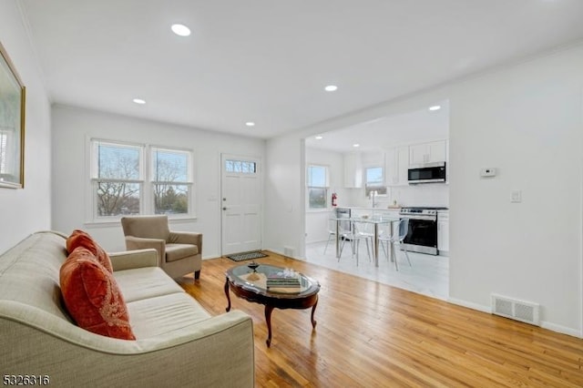 living area featuring a wealth of natural light, recessed lighting, visible vents, and light wood finished floors