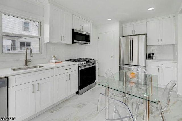 kitchen with white cabinets, marble finish floor, stainless steel appliances, light countertops, and a sink