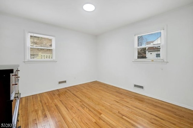 unfurnished room with a wealth of natural light, visible vents, and light wood-style flooring