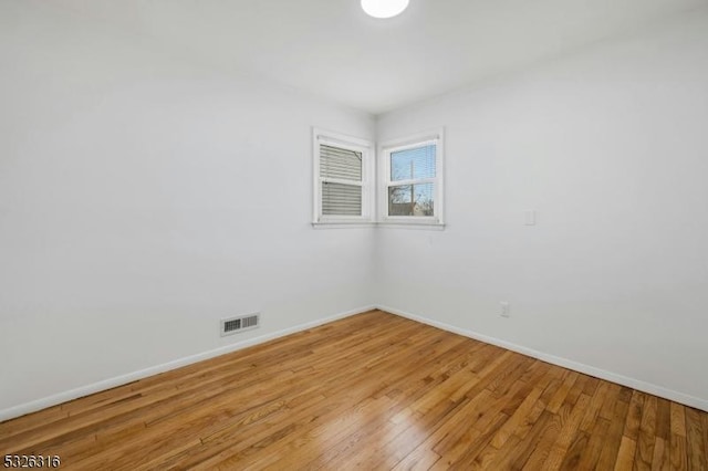 unfurnished room with light wood-style floors, visible vents, and baseboards