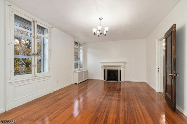 unfurnished living room with radiator, dark wood-type flooring, and an inviting chandelier