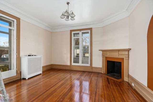 unfurnished living room featuring hardwood / wood-style flooring, radiator, ornamental molding, and a notable chandelier