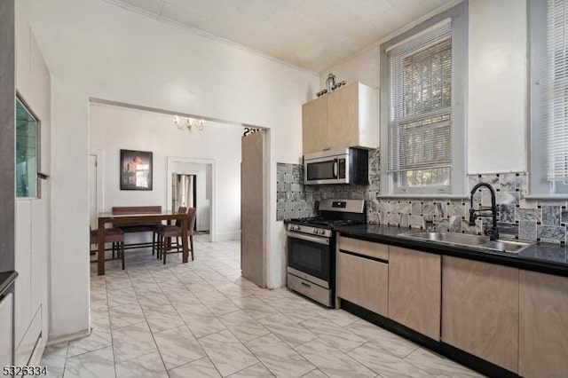 kitchen with appliances with stainless steel finishes, backsplash, crown molding, sink, and an inviting chandelier