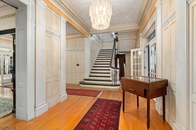 interior space with a notable chandelier, light wood-type flooring, and crown molding