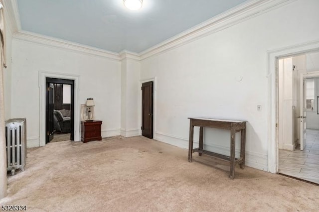 empty room with light colored carpet, radiator heating unit, and crown molding